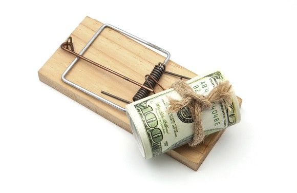 Roll of hundred dollar bills sitting on a mouse trap