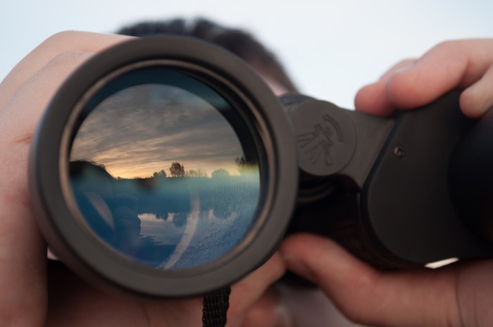 A man using binoculars to look into the distance. 