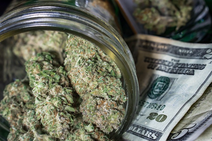 Marijuana in a mason jar with a lot of cash.