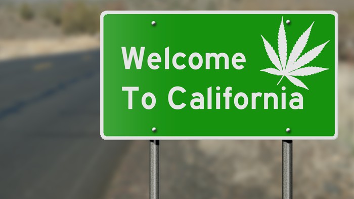 A highway sign that reads, Welcome to California, with a white cannabis leaf.
